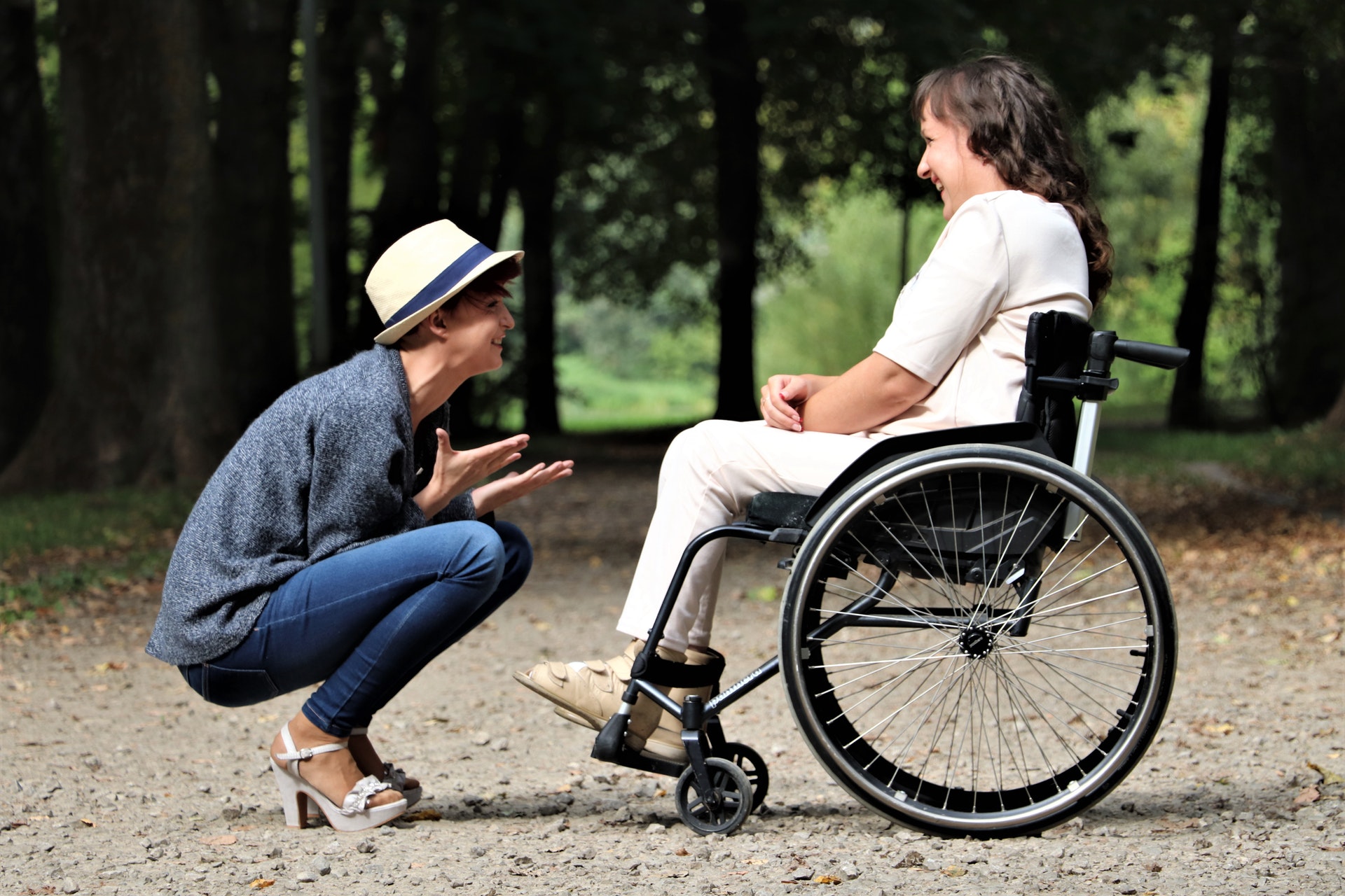 Imagen en la que aparecen dos personas sonrientes y felices, una de ellas en posición de cuclillas frente a la otra, que se encuentra sobre una silla de ruedas